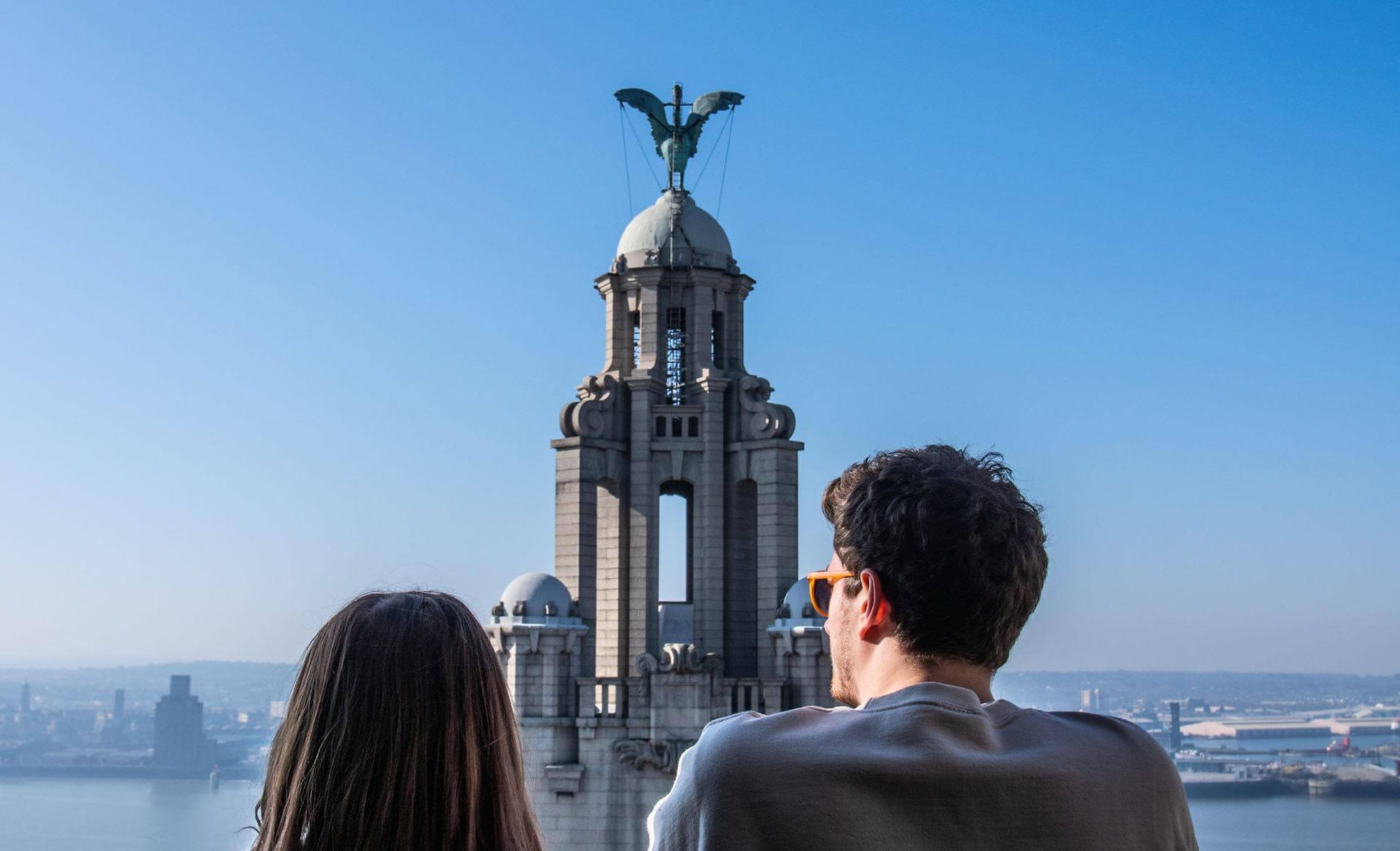 man and woman on the roof of the royal liver building looking over the River Mersey 